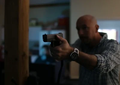 Participant aiming a tethered training pistol during a simulator session.