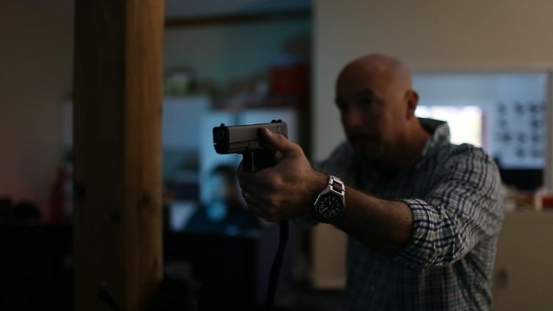 Participant aiming a tethered training pistol during a simulator session.