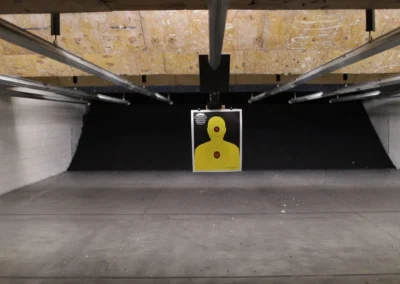 Suspended yellow target at the end of an indoor shooting lane.