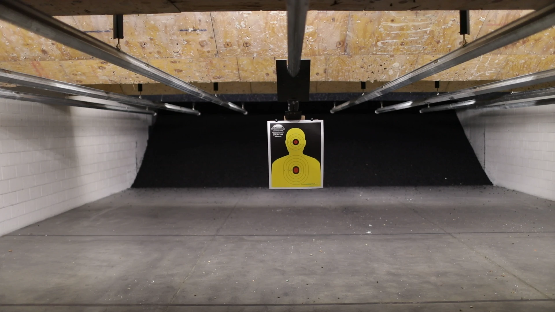 Suspended yellow target at the end of an indoor shooting lane.