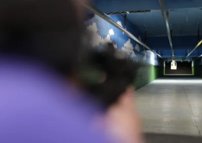 View down the indoor rifle range with a shooter in the foreground.